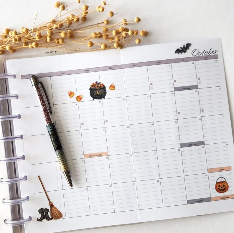 An October planner page decorated with Halloween Remembered stickers, beside a pen and dried flowers